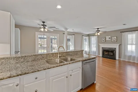 a kitchen with granite countertop a sink and white cabinets with wooden floor