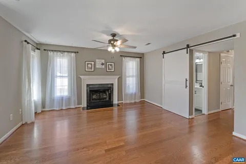a view of a livingroom with a fireplace wooden floor and a ceiling fan
