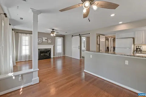 a view of a livingroom with a fireplace wooden floor and a kitchen