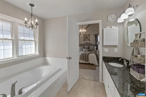 a en suite spacious bathroom with a tub double vanity and mirrors