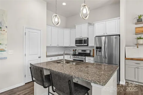 a kitchen with granite countertop a table chairs microwave and refrigerator