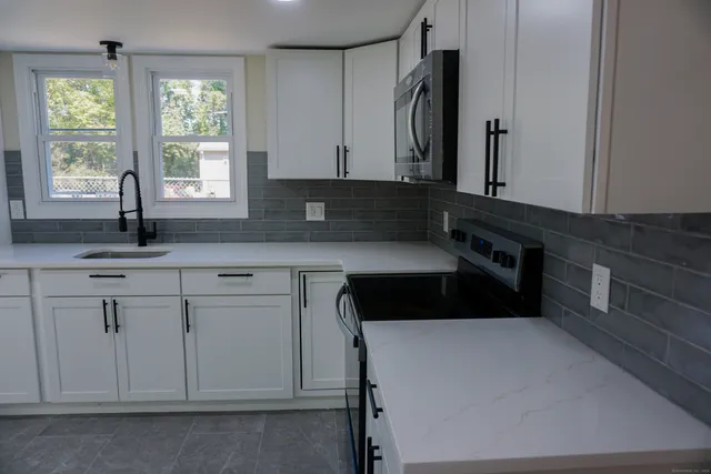 a kitchen with granite countertop a sink window and cabinets