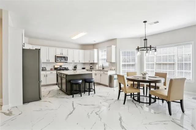 a dining room with stainless steel appliances kitchen island granite countertop a dining table chairs and a refrigerator