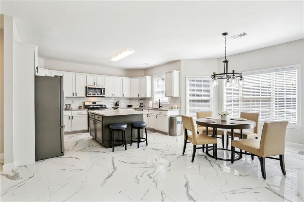 5161 Madison Green Drive Southwest Mableton, GA 30126 - Photo 13 of 40 a dining room with stainless steel appliances kitchen island granite countertop a dining table chairs and a refrigerator
