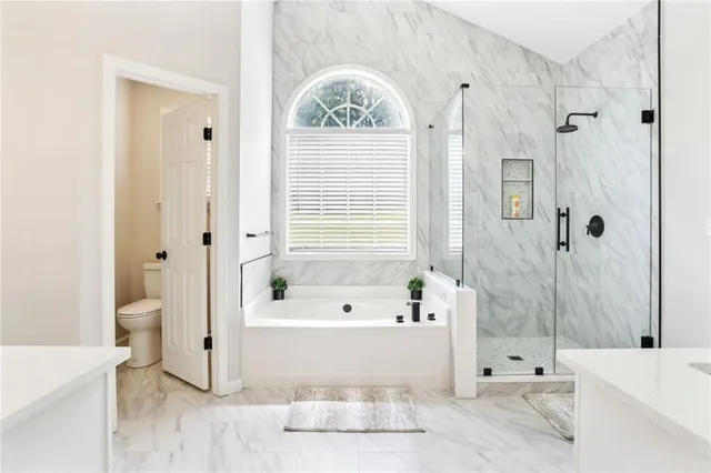 a bathroom with a tub a toilet and a window