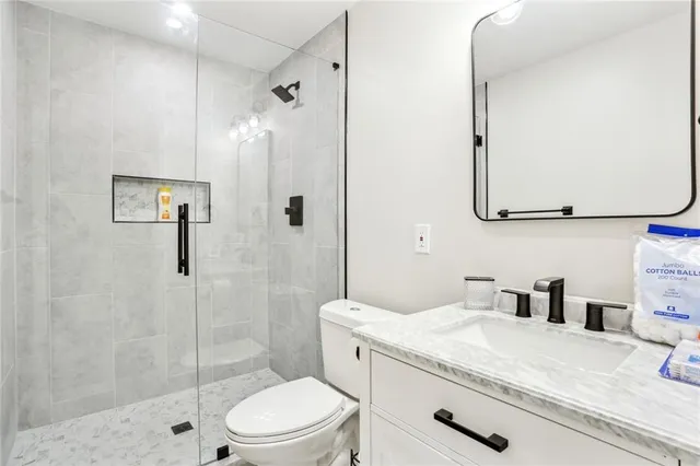 a bathroom with a granite countertop sink a toilet and shower