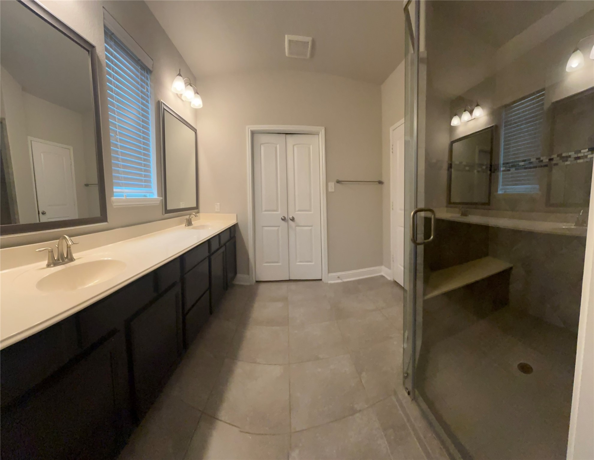 14915 Gyrfalcon Fork Cypress, TX 77429 - Photo 12 of 24 Spacious primary bathroom featuring a double vanity, sleek glass-enclosed shower, and modern lighting. Perfect for relaxation and convenience.