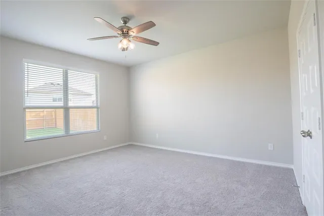 an empty room with a window and a ceiling fan