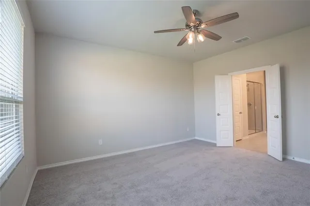 an empty room with a window and a ceiling fan