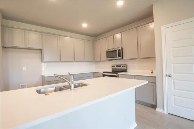 a kitchen with stainless steel appliances a sink a stove a microwave a sink a refrigerator and cabinets