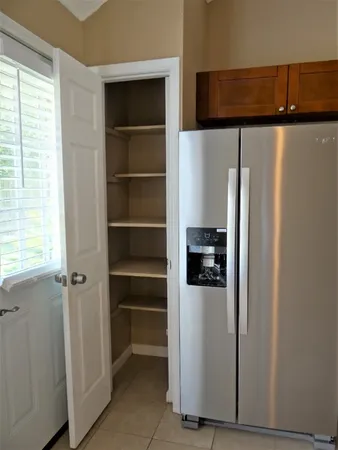 a view of a refrigerator in kitchen and a window in a room