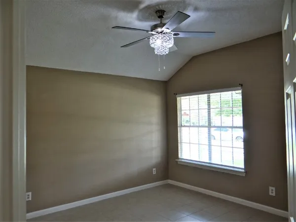 an empty room with chandelier fan and windows