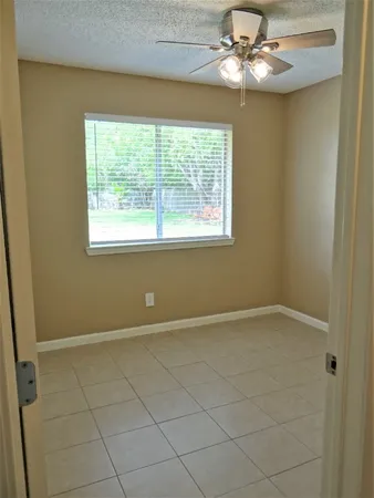 an empty room with windows and fan
