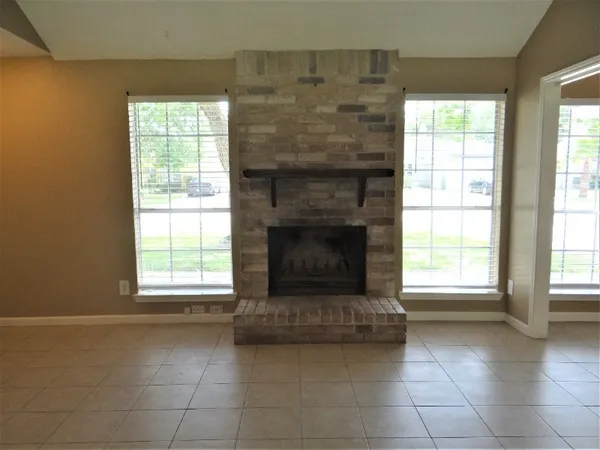 an empty room with windows and fireplace