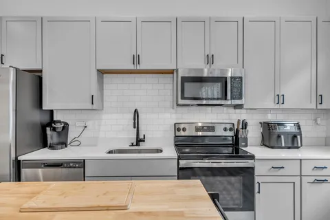 a kitchen with stainless steel appliances granite countertop a stove a sink and a microwave