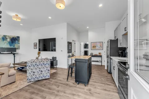 a living room with furniture a flat screen tv and kitchen view