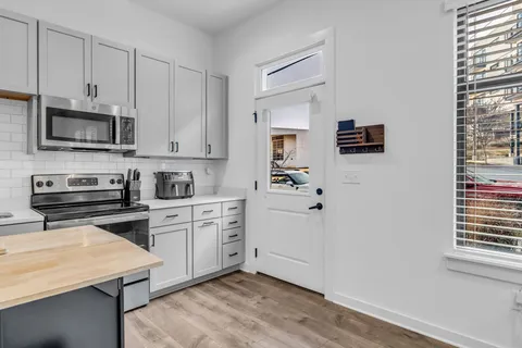 a kitchen with cabinets stainless steel appliances and wooden floor