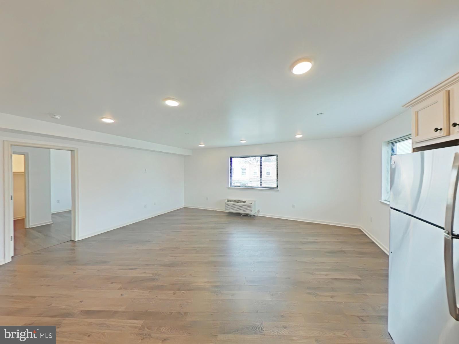5420 Ridge Avenue, Unit 409 Philadelphia, PA 19128 - Photo 3 of 13 an empty room with wooden floor and a refrigerator