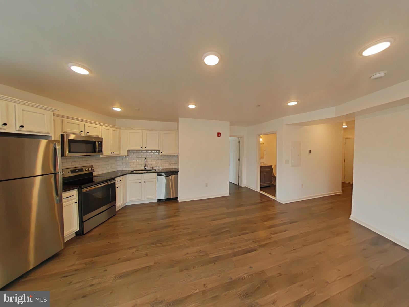 5420 Ridge Avenue, Unit 409 Philadelphia, PA 19128 - Photo 4 of 13 a large kitchen with stainless steel appliances granite countertop a refrigerator and a stove top oven