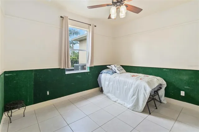a bed sitting in a spacious bedroom next to a window and a table