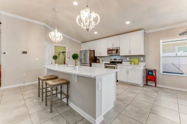 a kitchen with kitchen island granite countertop stainless steel appliances a sink a stove a counter top space cabinets and a window