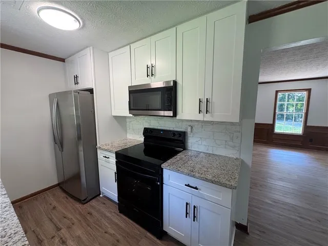 a kitchen with granite countertop a refrigerator stove and microwave