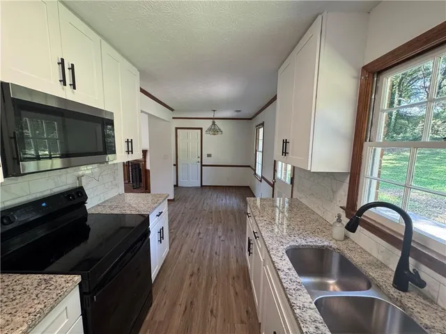 a kitchen with granite countertop a sink wooden floor and stainless steel appliances