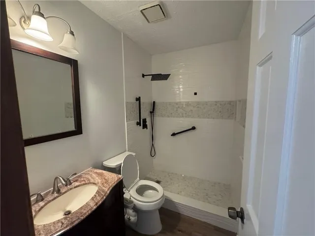 a bathroom with a granite countertop sink toilet and mirror