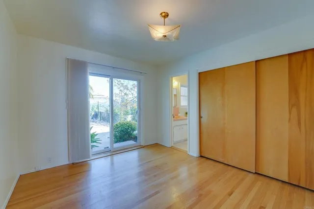 a view of an empty room with wooden floor and a bathroom