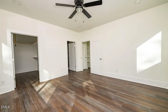 a view of empty room with wooden floor and fan