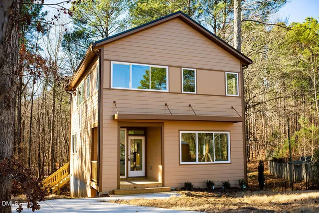 a view of a white house with large windows next to a road
