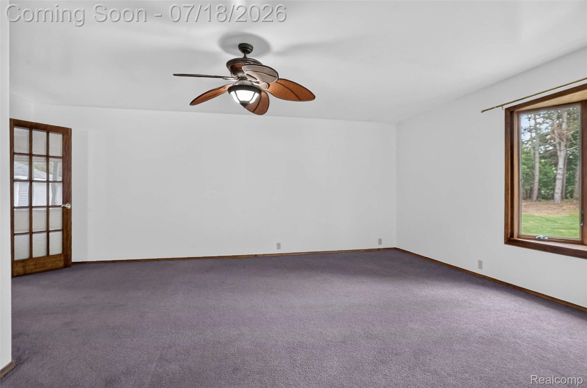 1437 East Cook Road Grand Blanc, MI 48439 - Photo 53 of 69 Spacious room featuring a ceiling fan with integrated lighting, a multi-pane French door, a large window with wood trim, and wall-to-wall carpeting