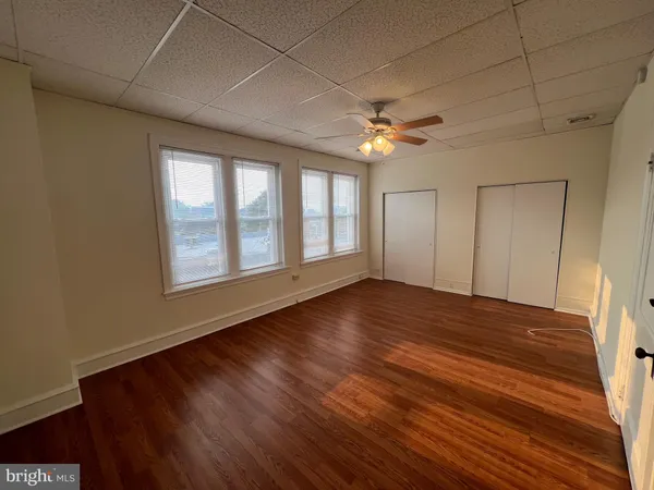 a view of empty room with wooden floor and fan
