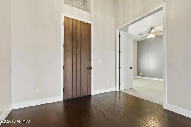 an empty room with wooden floor a ceiling fan and windows