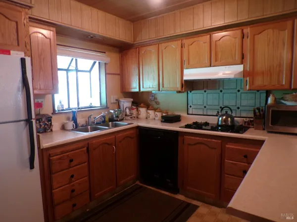 a kitchen with stainless steel appliances a sink dishwasher a refrigerator cabinets and a window