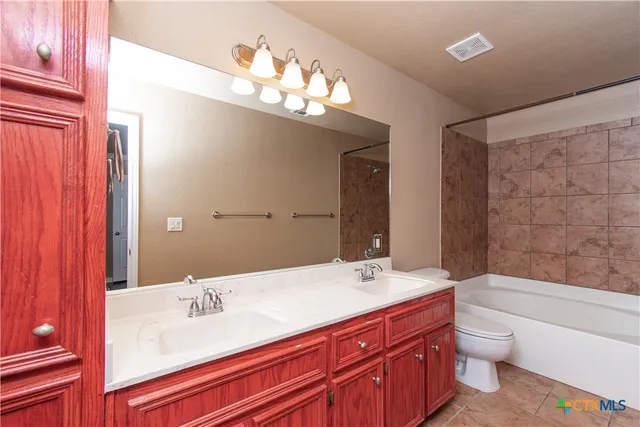a bathroom with a granite countertop sink a toilet a large mirror and shower