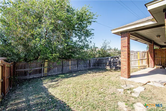 a view of a backyard with wooden fence and a trees