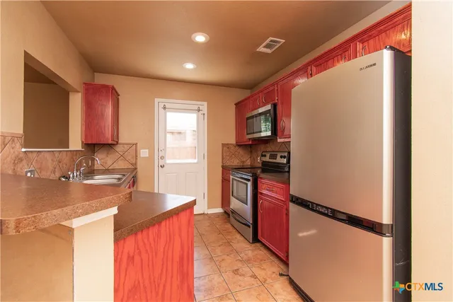 a kitchen with stainless steel appliances granite countertop a refrigerator and a sink
