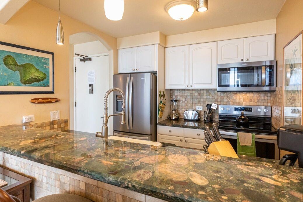 191 North Kihei Road, Unit 502 Kihei, HI 96753 - Photo 14 of 37 a kitchen with stainless steel appliances granite countertop a refrigerator a stove and a sink with wooden cabinets