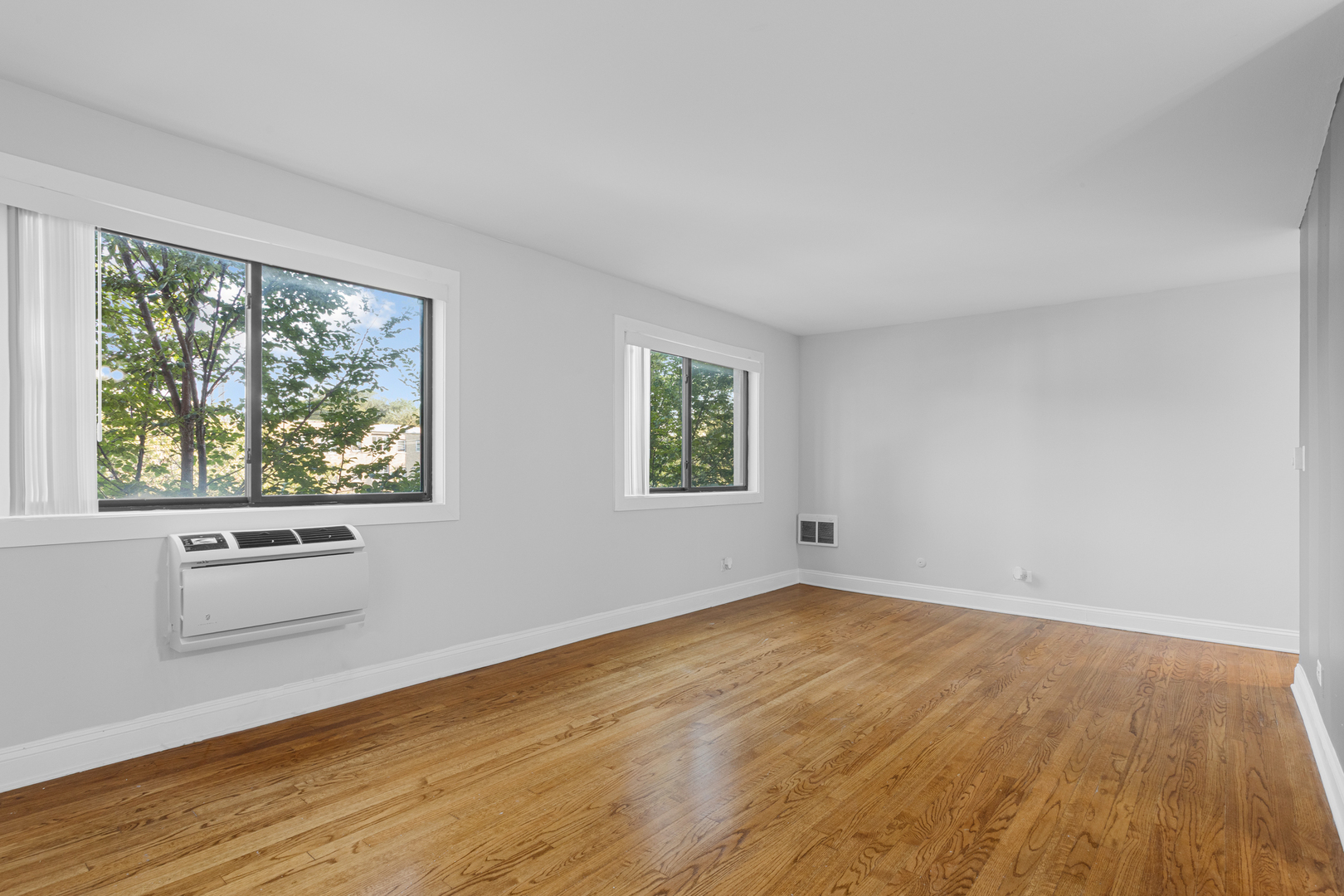 7545 North Winchester Avenue, Unit 303 Chicago, IL 60626 - Photo 5 of 13 an empty room with wooden floor and windows