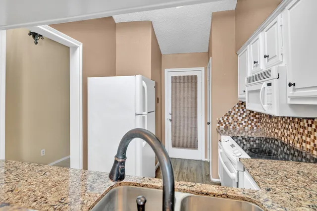 a kitchen with white cabinets and sink