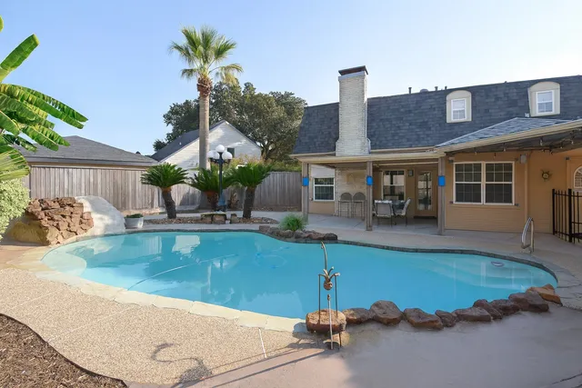 a view of a house with pool plants and chairs