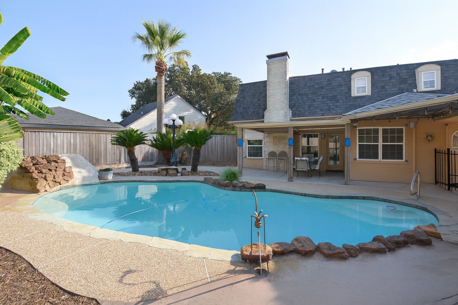 a view of a house with pool plants and chairs