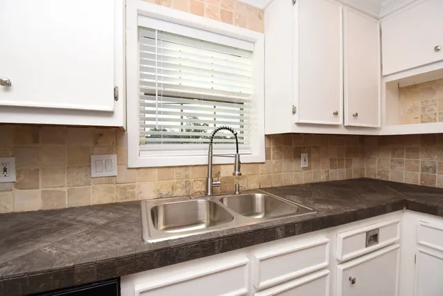 a kitchen with stainless steel appliances granite countertop white cabinets granite counter tops and a wooden floors