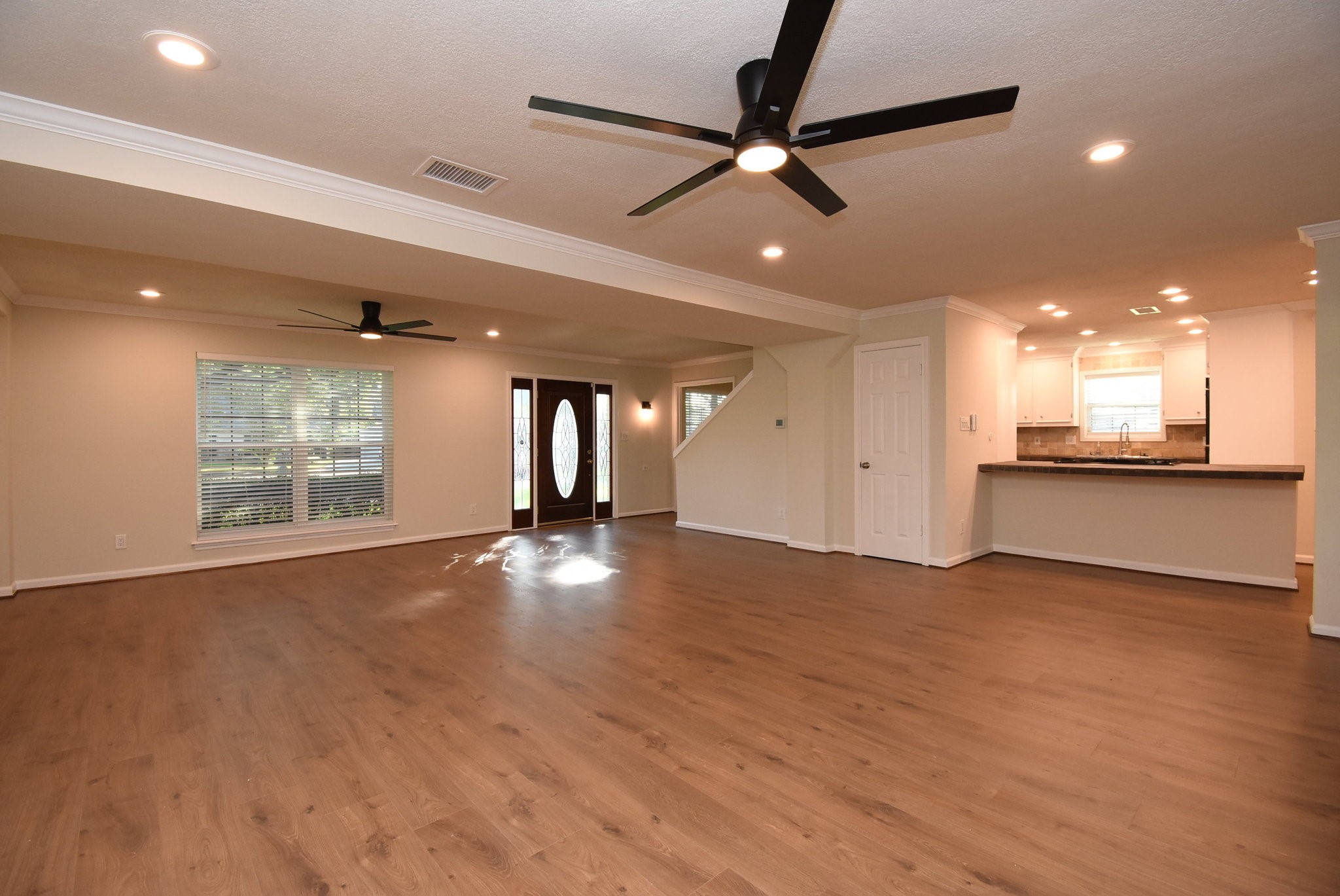 2503 Southwick Street Houston, TX 77080 - Photo 10 of 46 an empty room with wooden floor a ceiling fan and kitchen view
