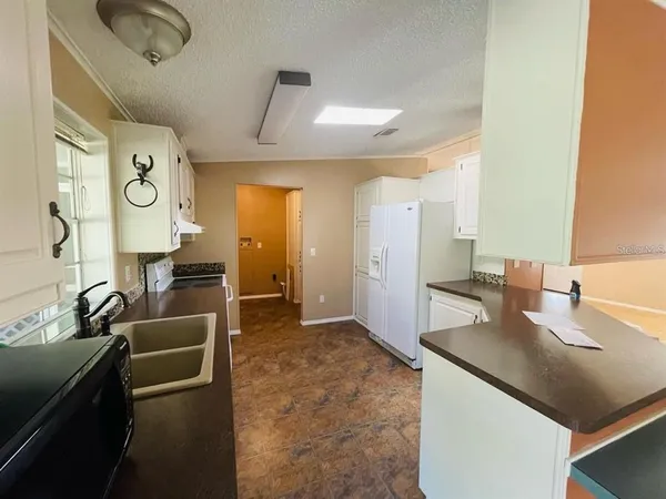 a living room with stainless steel appliances kitchen island granite countertop a sink and dishwasher a refrigerator with wooden floor