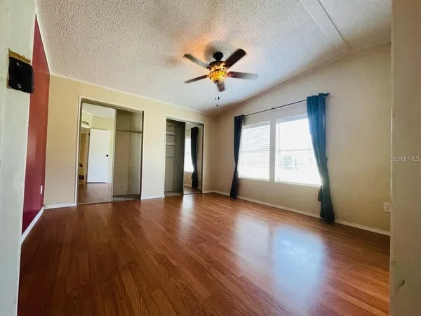 a view of an empty room with a window and wooden floor