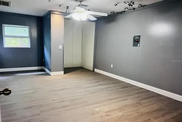 an empty room with wooden floor closet and windows