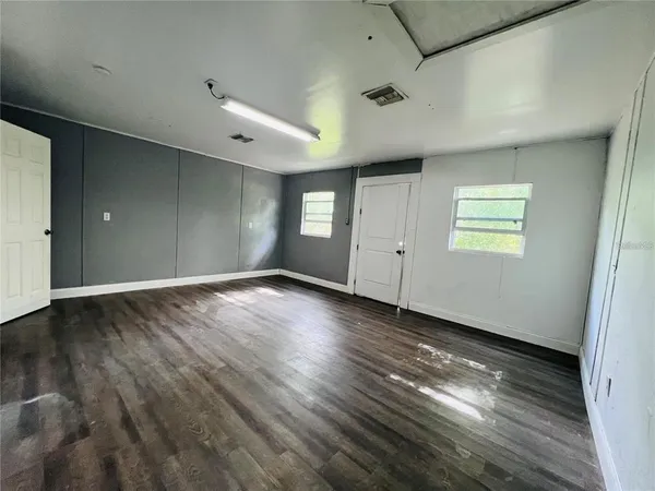 an empty room with wooden floor and windows