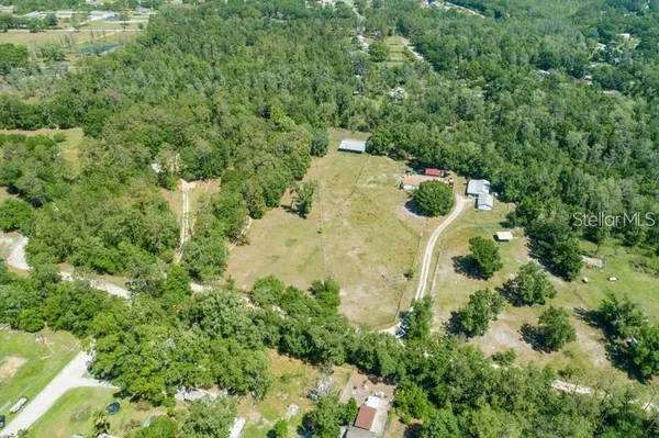 an aerial view of residential house with outdoor space and trees all around